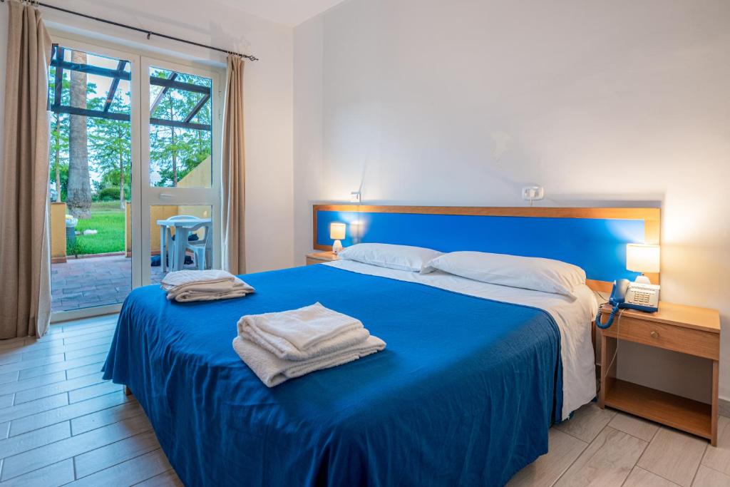 une chambre avec un lit bleu avec des serviettes dessus dans l'établissement La Feluca, à Isca sullo Ionio