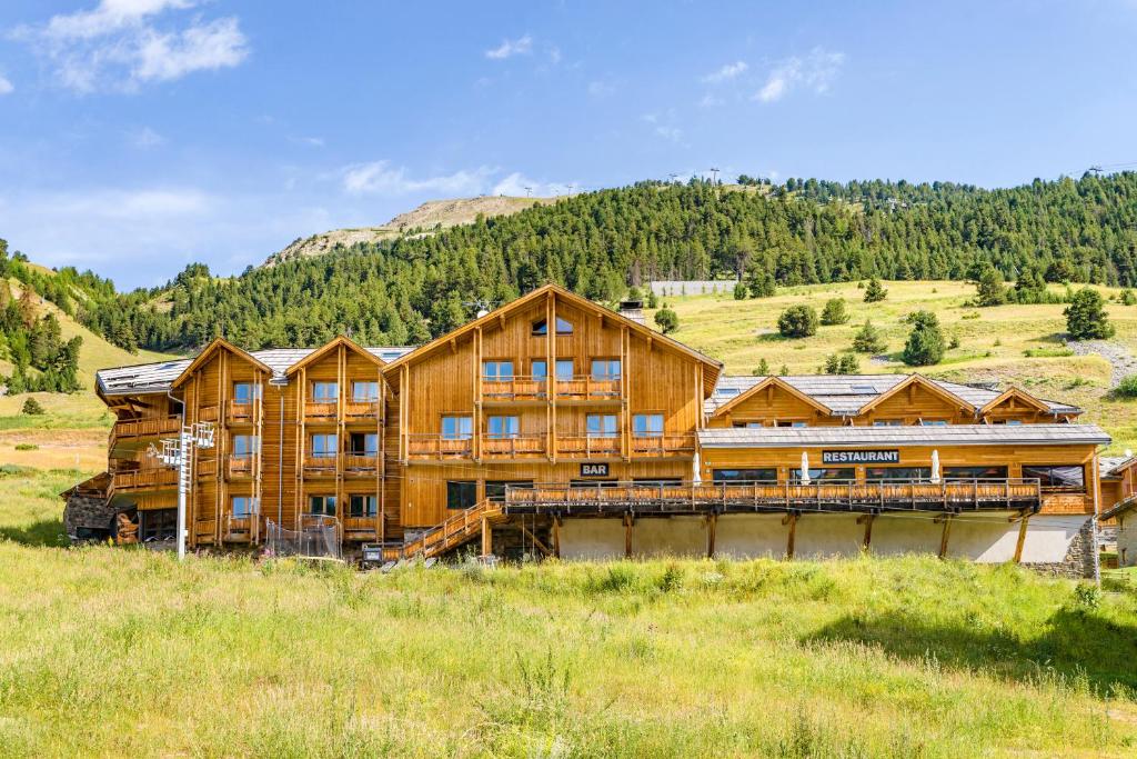 un grand chalet en rondins dans un champ d'herbe dans l'établissement Anova Hotel & Spa, à Montgenèvre
