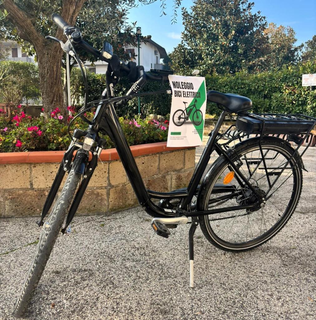 un vélo garé sur un trottoir à côté d'un panneau dans l'établissement Aparthotel Costa Paradiso, à Lido Adriano
