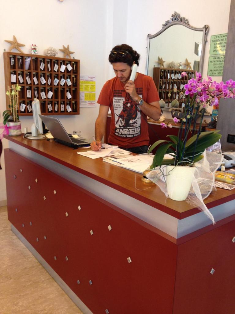 Un homme qui parle sur un téléphone à un comptoir dans un magasin dans l'établissement Hotel Sogno, à Cesenatico