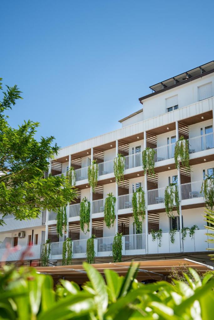 un immeuble avec des plantes sur les balcons dans l'établissement Hotel Renania, à Bibione