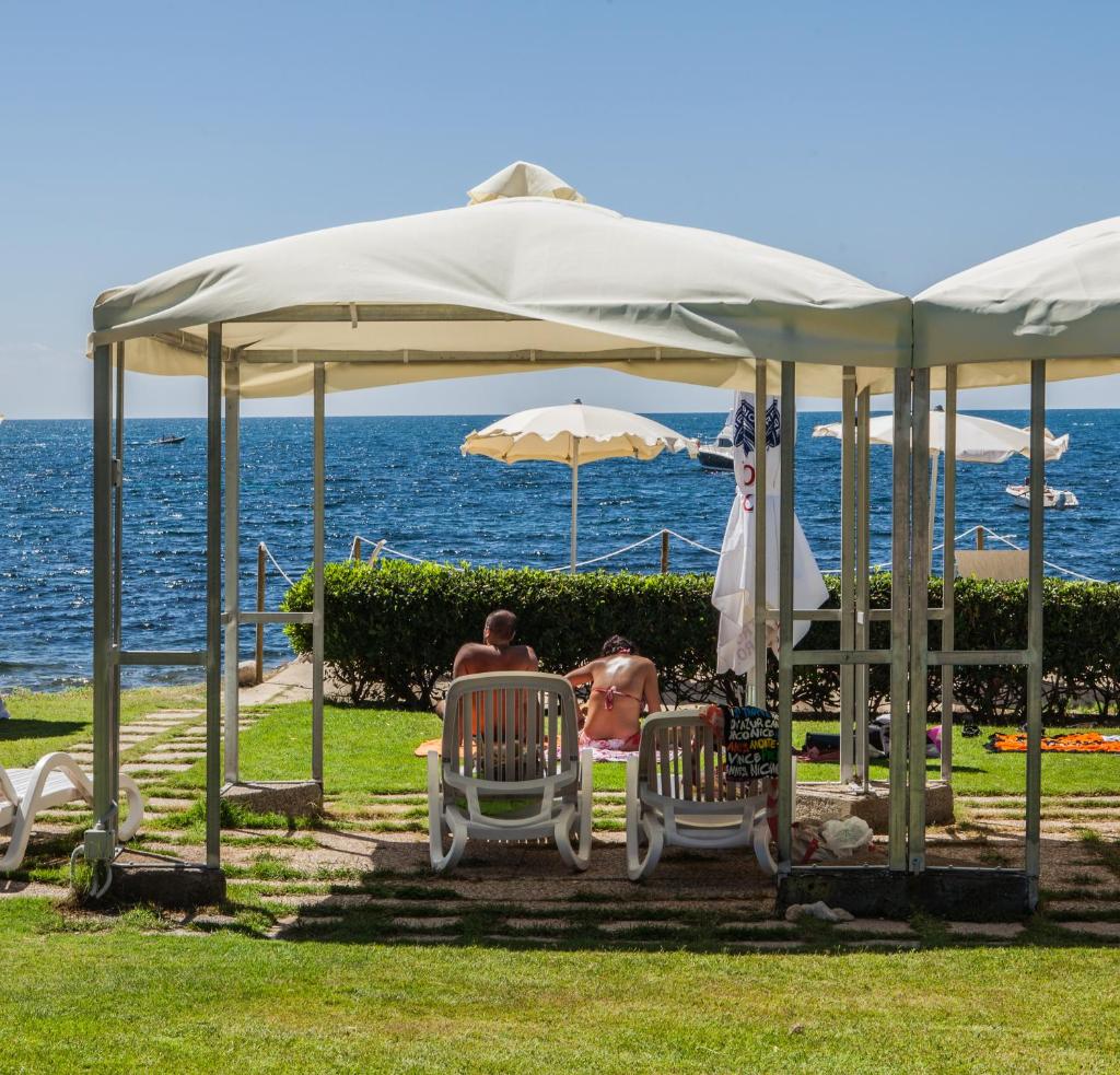 deux personnes assises sur des chaises sous un parasol dans l'établissement Hotel Calamosca, à Cagliari 61 autres photos