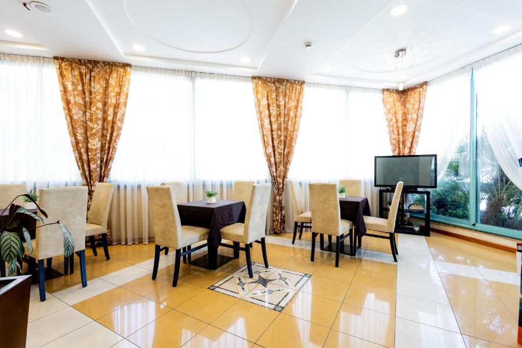 une salle à manger avec tables et chaises et une télévision dans l'établissement Hotel Palm Beach B&B SEA VIEW, à Rimini