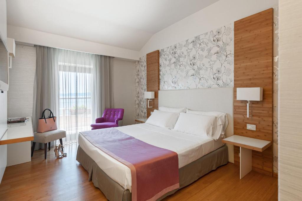 une chambre d'hôtel avec un lit et une chaise violette dans l'établissement Hotel Eden, à Sirmione