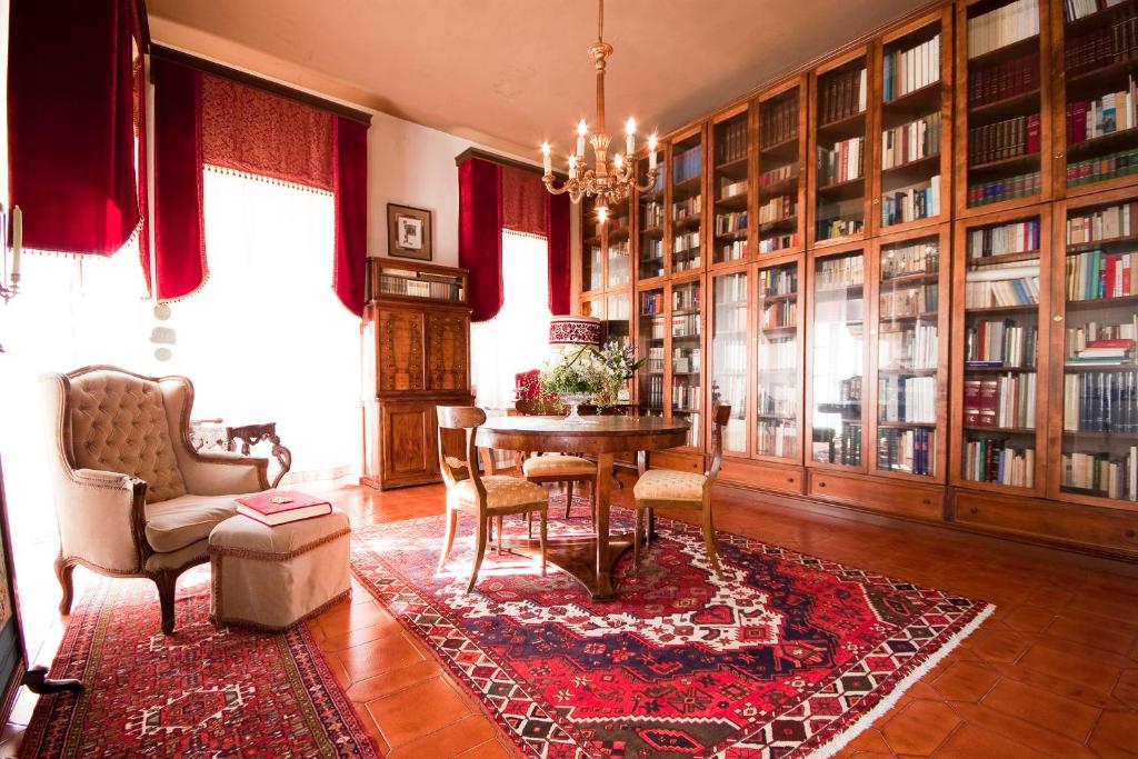 une bibliothèque avec une table, des chaises et des étagères dans l'établissement Villa Sogara, à San Martino Buon Albergo