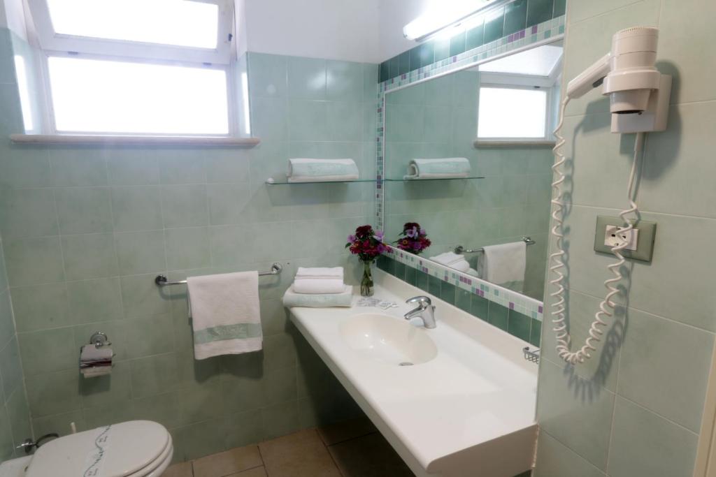 une salle de bain avec un lavabo, des toilettes et un miroir dans l'établissement Resort Sciabache, à Zambrone