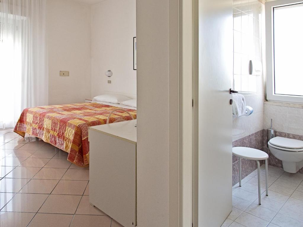 - une chambre blanche avec un lit et des toilettes dans l'établissement Hotel Radar, à Rimini