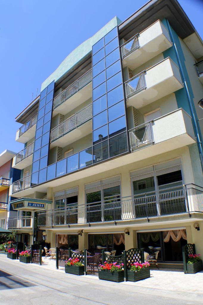 un immeuble d'appartements avec des fleurs devant dans l'établissement Hotel Adria, à Bellaria-Igea Marina