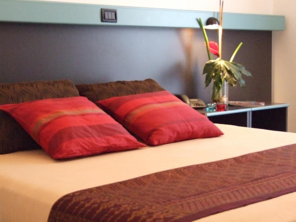 - 2 oreillers rouges assis au-dessus du lit dans l'établissement GFH - Hotel Ruhig, à Marotta