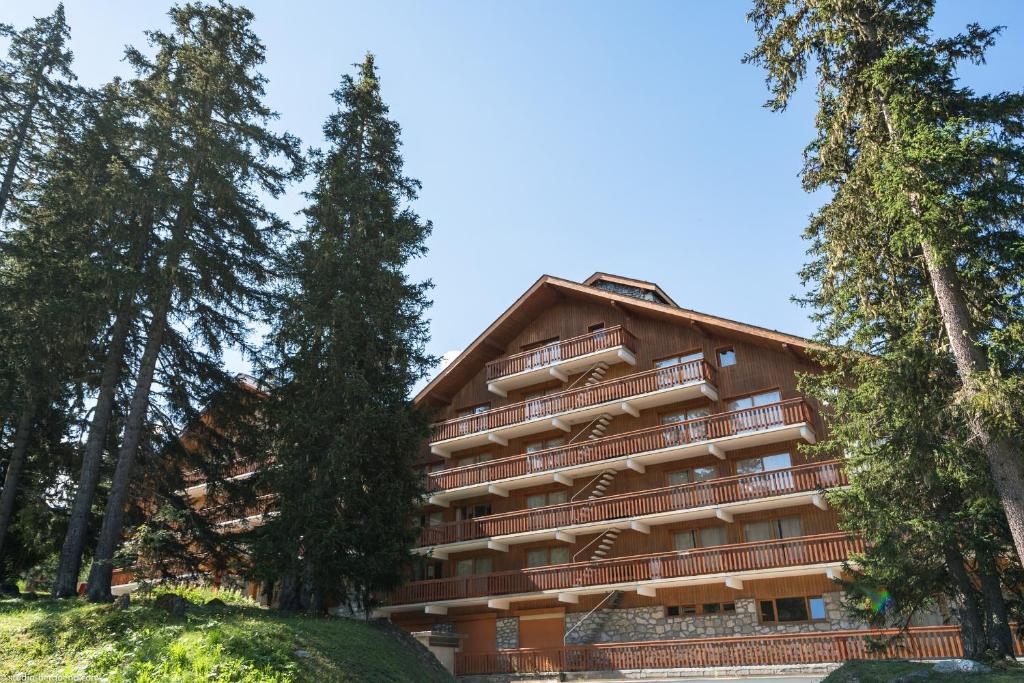 un bâtiment avec des arbres devant dans l'établissement Résidence partenaire Le Golf, à Méribel