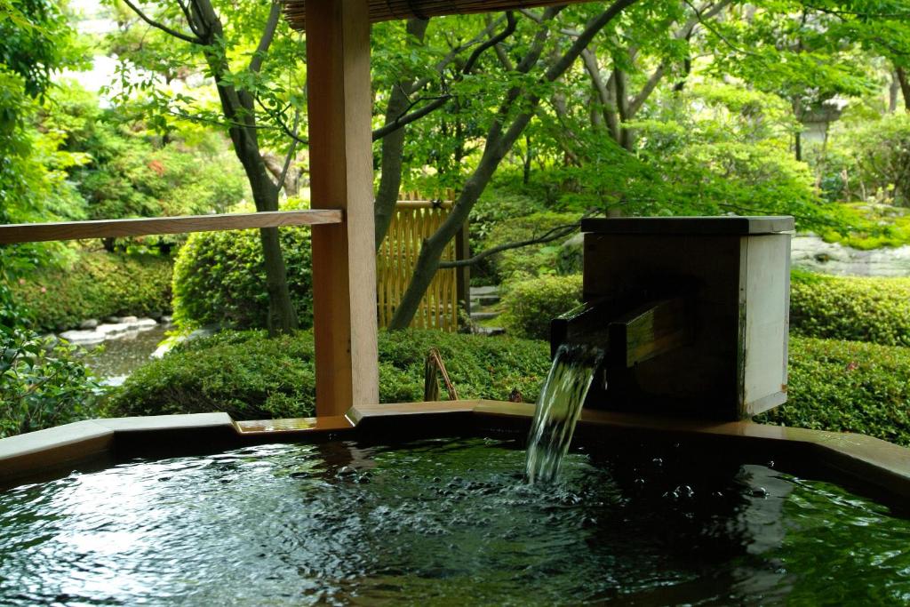 un étang avec une fontaine dans le jardin dans l'établissement Grandia Housen, à Awara