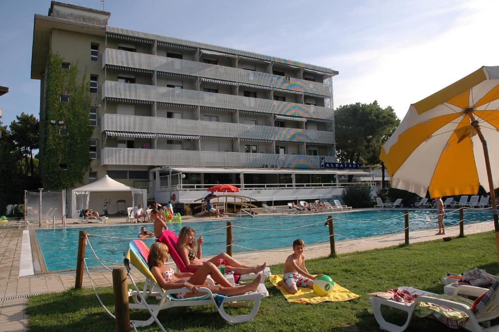 un groupe de personnes assises sur des chaises longues au bord de la piscine dans l'établissement Aparthotel Albatros, à Lignano Sabbiadoro