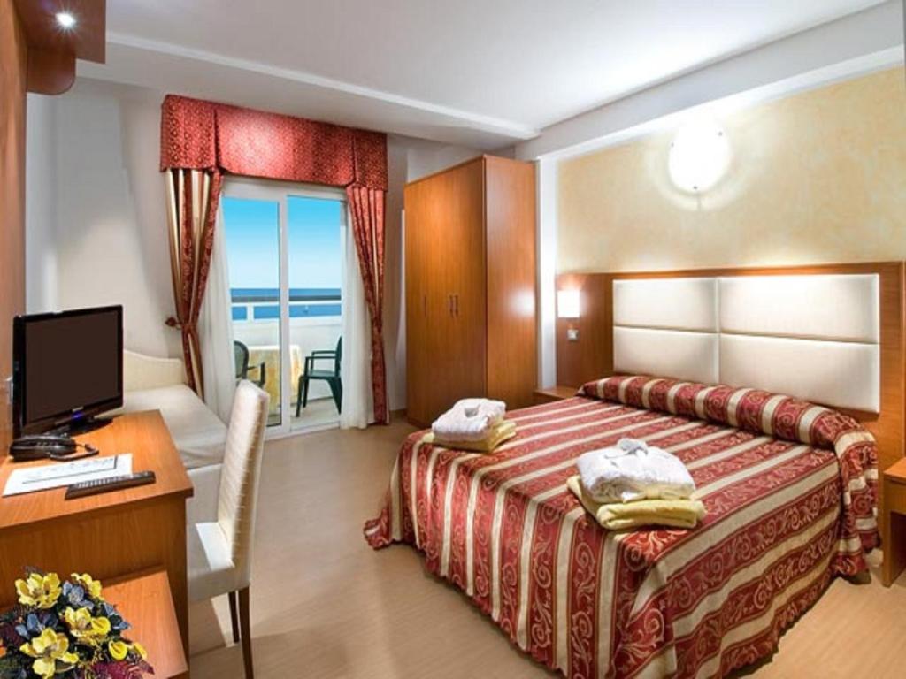 une chambre d'hôtel avec un lit, un bureau et un ordinateur dans l'établissement Strand Hotel Colorado, à Lido di Savio