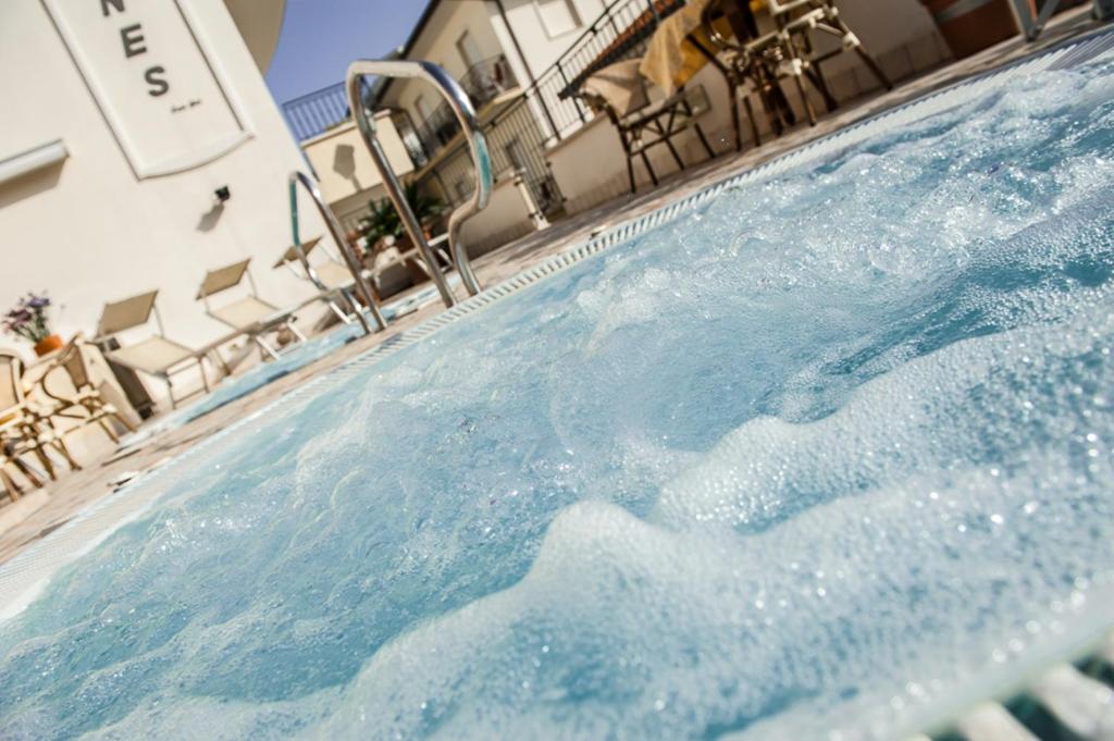 une piscine avec de l'eau bleue devant un immeuble dans l'établissement Hotel Cannes, à Bellaria-Igea Marina