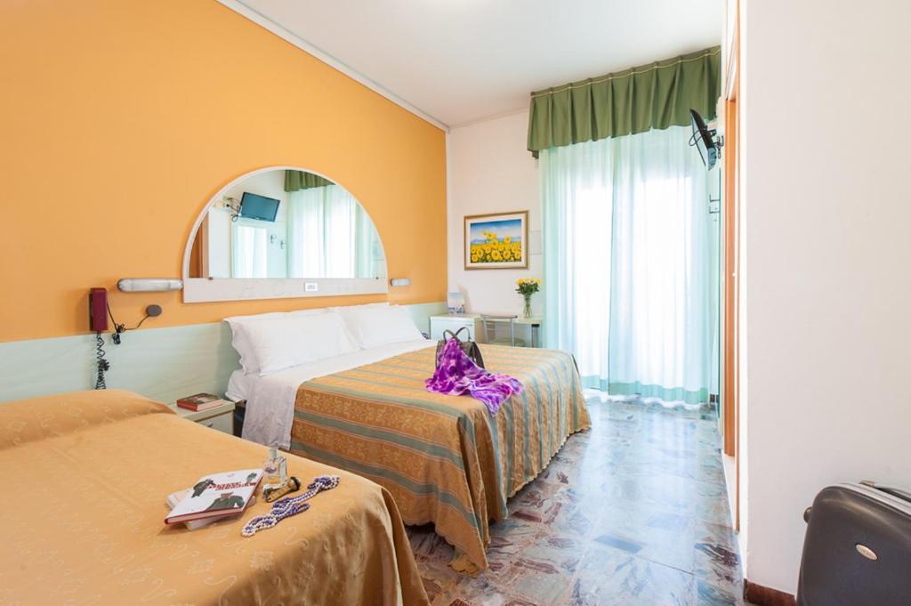 une chambre d'hôtel avec deux lits et un miroir dans l'établissement Hotel Cannes, à Bellaria-Igea Marina