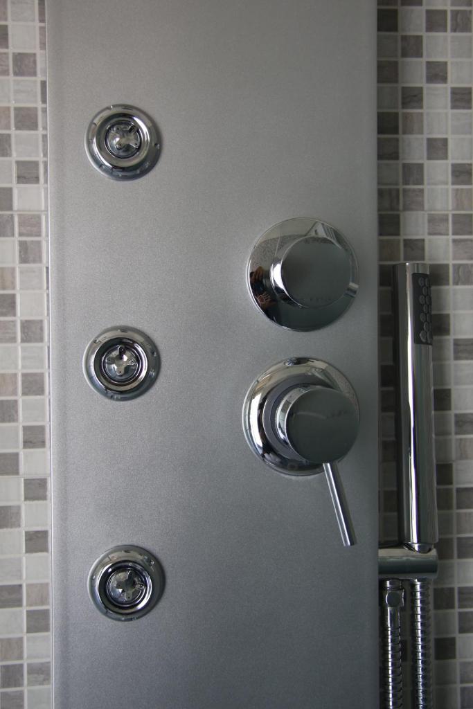 une douche avec des boutons argentés sur un mur dans l'établissement ChrisMare Hotel, à Mazzeo