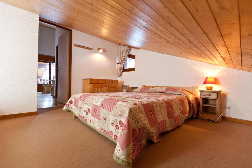 une chambre avec un lit et un plafond en bois dans l'établissement Azureva La Clusaz les Aravis, à La Clusaz