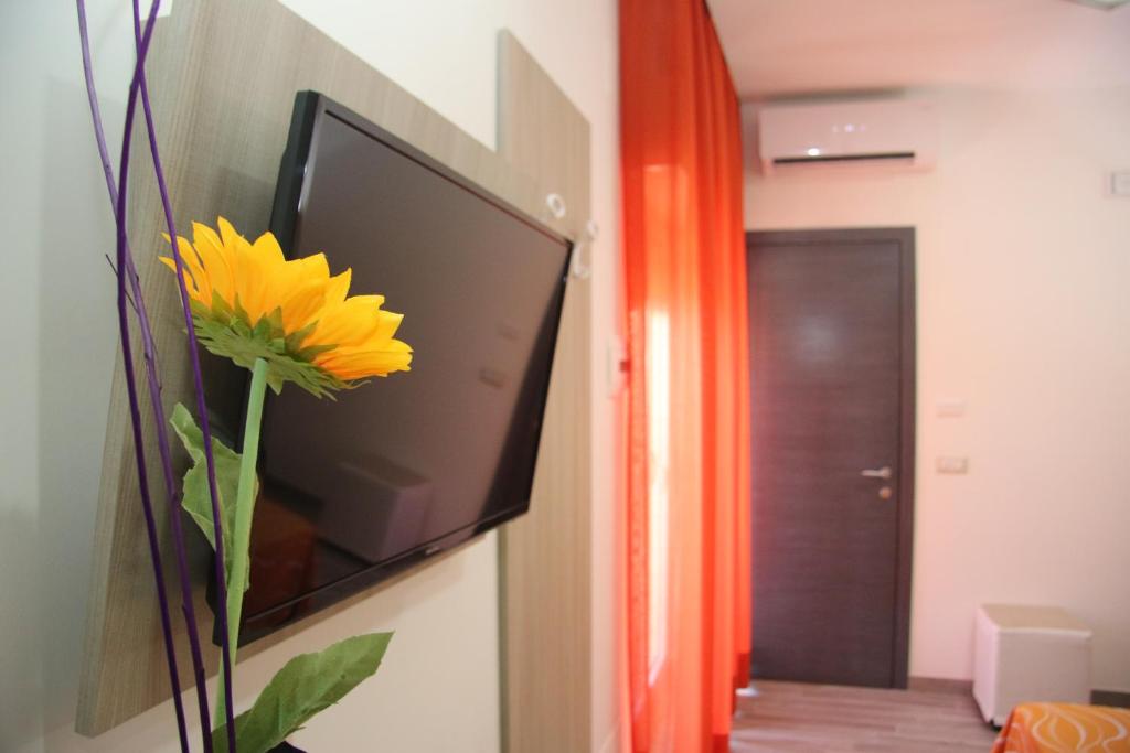 un vase avec une fleur jaune devant une télévision dans l'établissement ChrisMare Hotel, à Mazzeo
