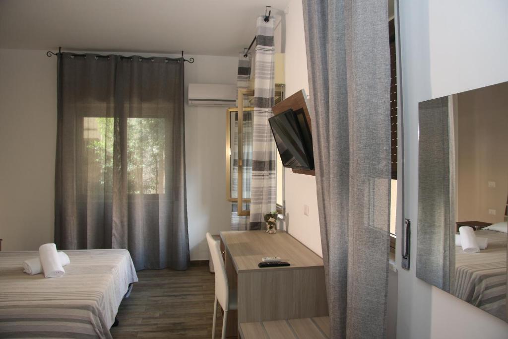 une chambre avec deux lits, un bureau et une télévision dans l'établissement ChrisMare Hotel, à Mazzeo