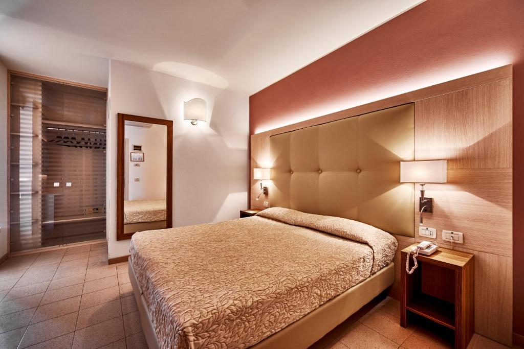 une chambre avec un grand lit et un miroir dans l'établissement Palace Hotel Regina, à Bibione