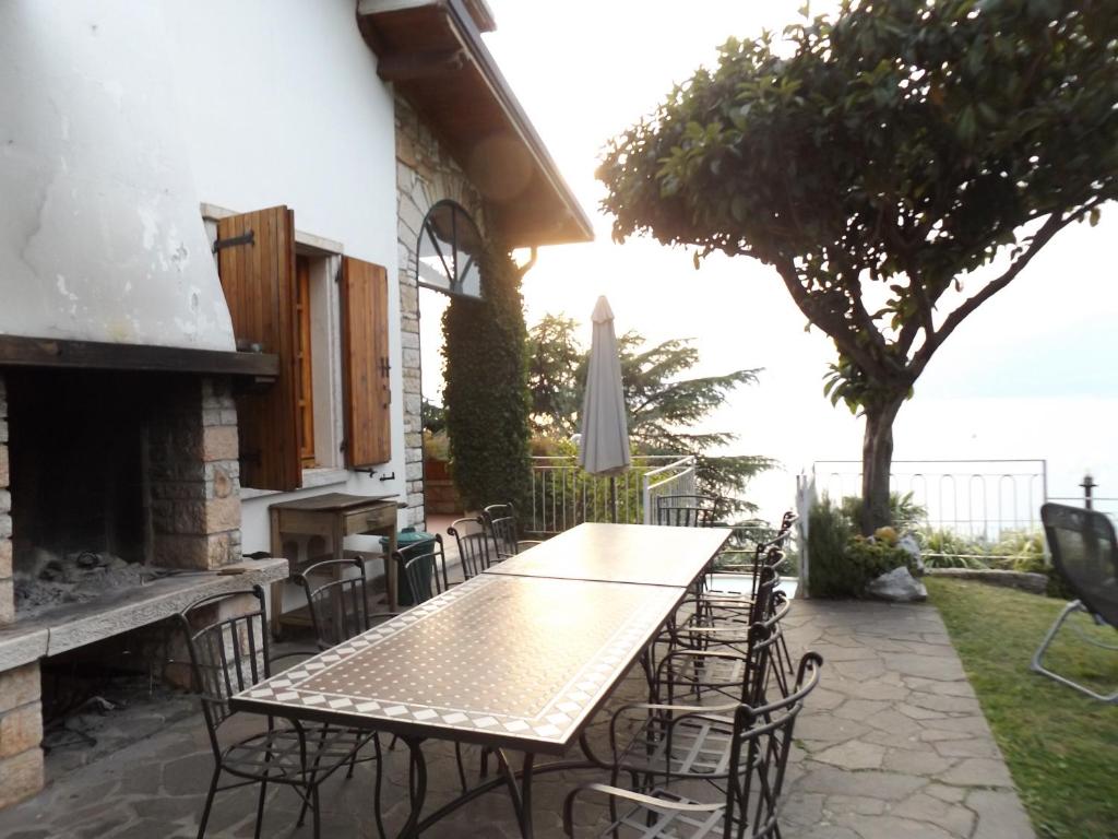 une table et des chaises sur une terrasse avec une cheminée dans l'établissement Villa Margiò, à Torri del Benaco