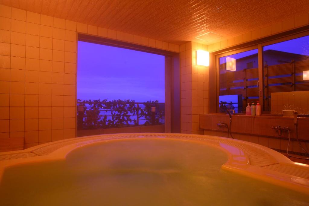 une grande baignoire dans une salle de bain avec une fenêtre dans l'établissement Eihokaku, à Himi