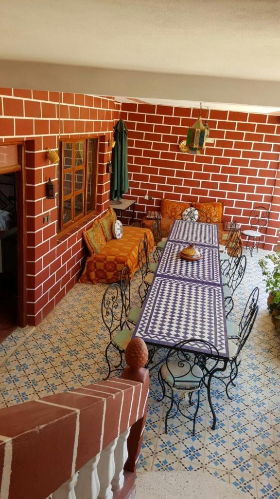 un patio avec une table et des chaises et un mur de briques dans l'établissement Kasabah Senhaji, à Moulay Idriss Zerhoun