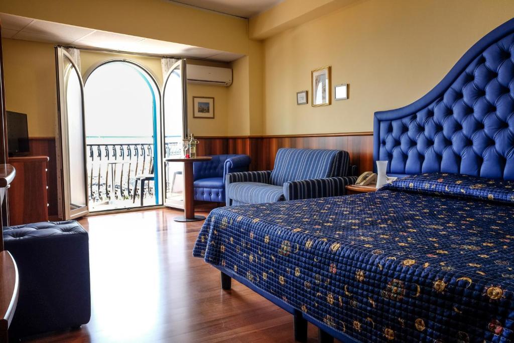 une chambre avec un lit bleu et un balcon dans l'établissement Hotel Nike, à Giardini Naxos