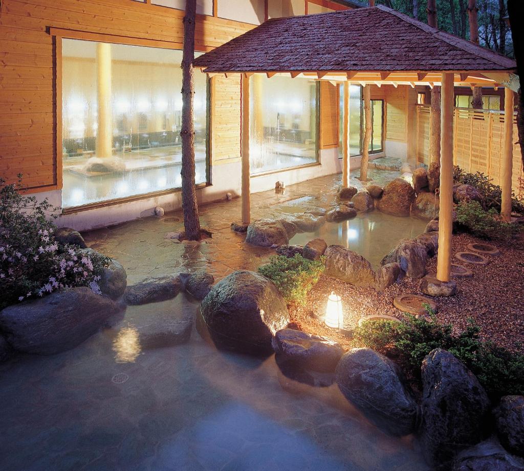 un jardin avec un étang en face d'un bâtiment dans l'établissement Tateyama Prince Hotel, à Omachi