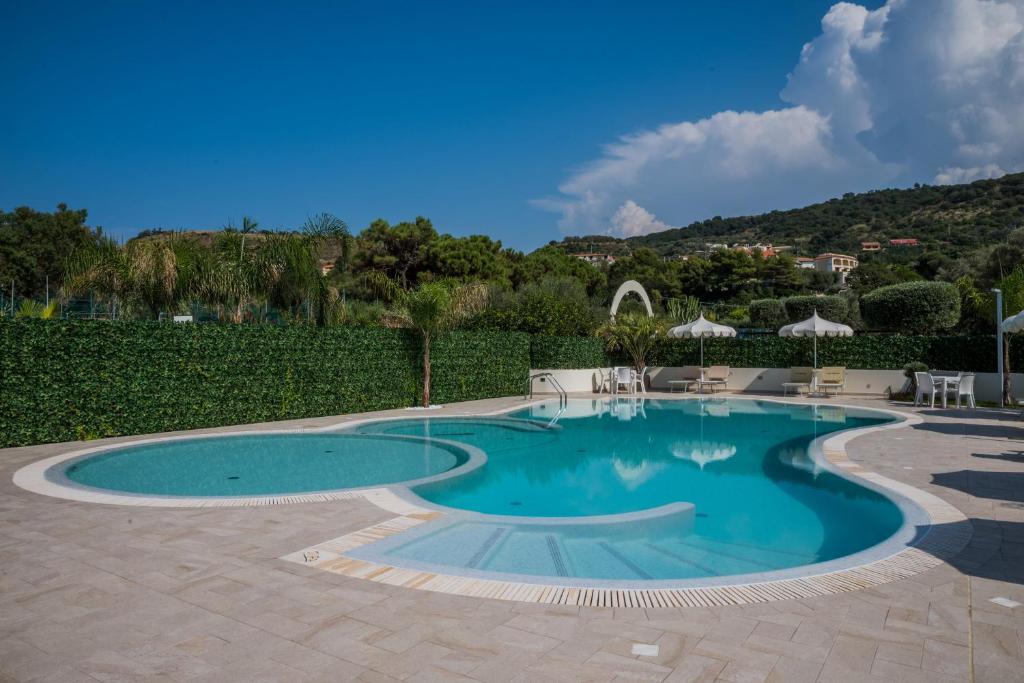 - une piscine dans une cour avec des chaises et des parasols dans l'établissement Blu Tropical Resort, à Zambrone
