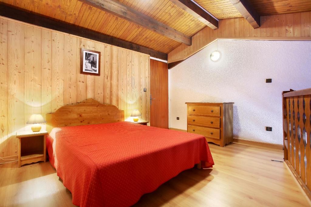 - une chambre avec un lit rouge et un mur en bois dans l'établissement Résidence Odalys Le Front de Neige, aux Carroz d'Arâches