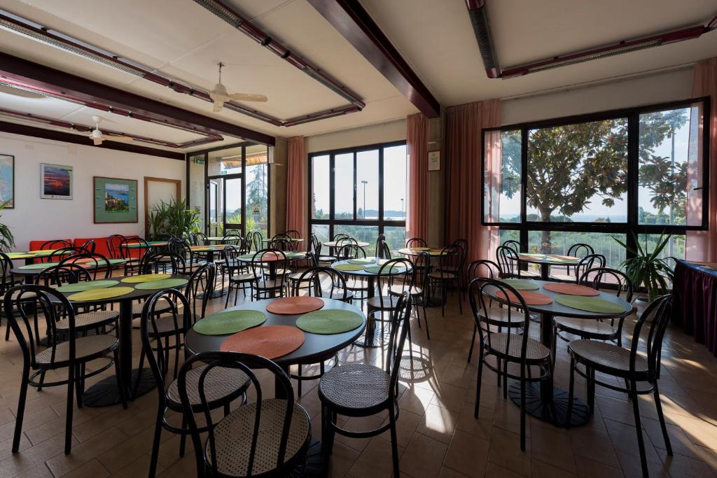 une pièce avec des tables, des chaises et des fenêtres dans l'établissement Hotel Le Tre Isole, à Magione