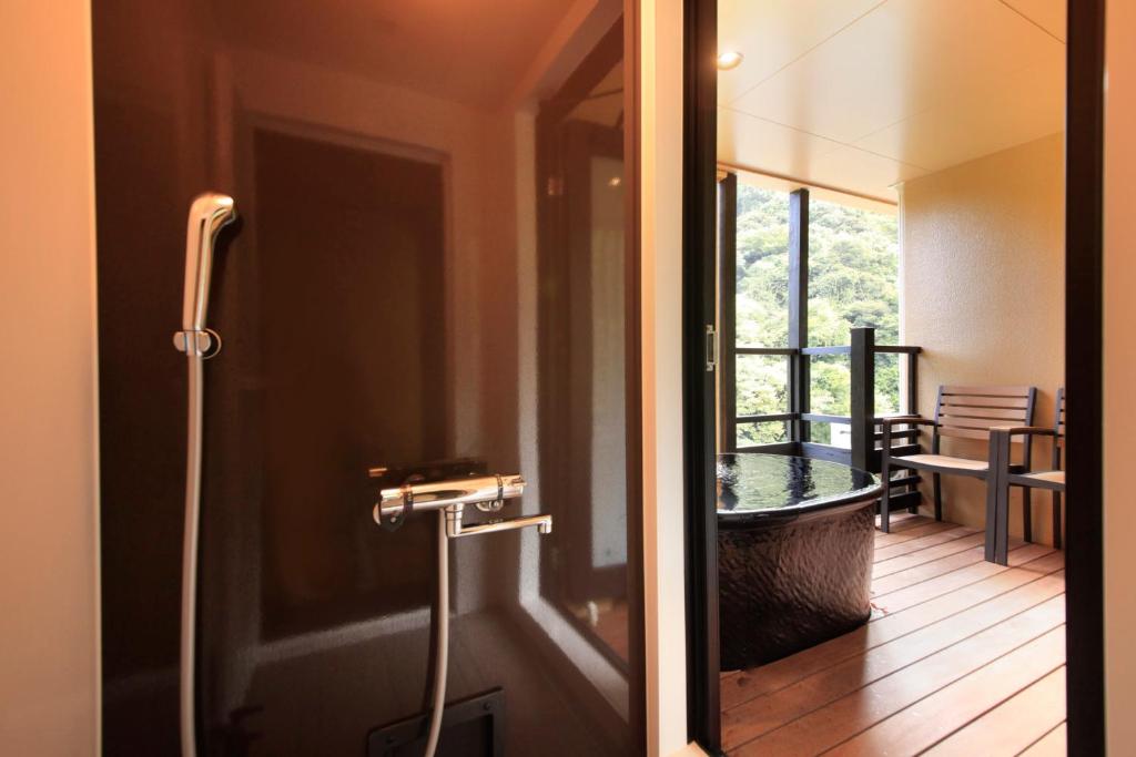 une porte menant à un balcon avec une baignoire. dans l'établissement Hakone Suimeisou, à Hakone