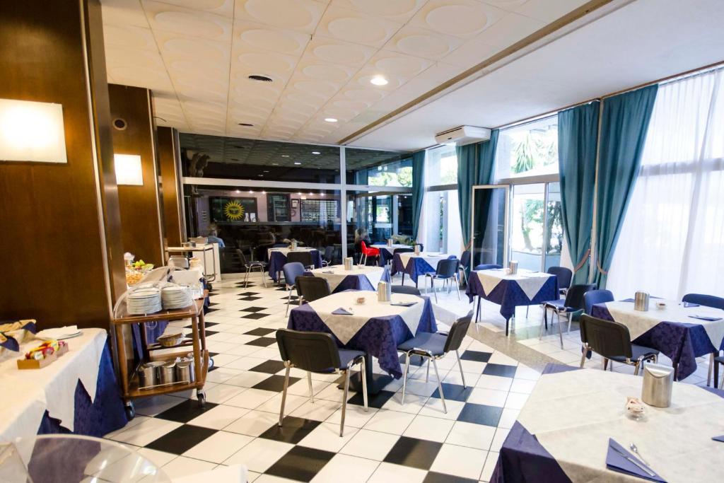 une salle à manger avec tables, chaises et fenêtres dans l'établissement Grand Hotel Helios, à Tarquinia