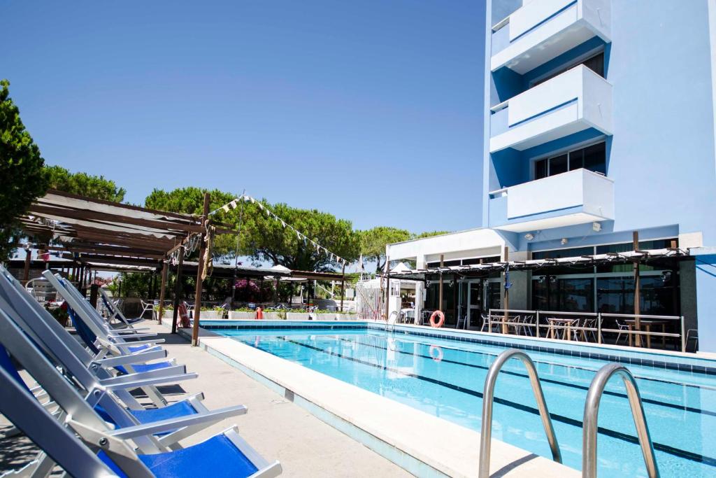 une piscine avec des chaises longues à côté d'un bâtiment dans l'établissement Grand Hotel Helios, à Tarquinia