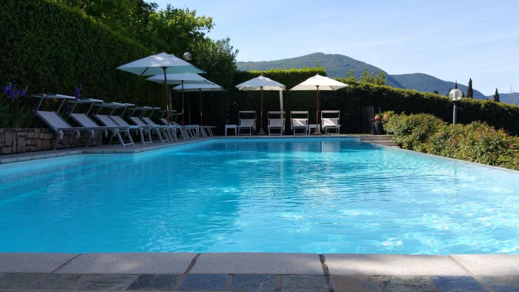 une grande piscine bleue avec chaises et parasols dans l'établissement Villa Kinzica, à Sale Marasino