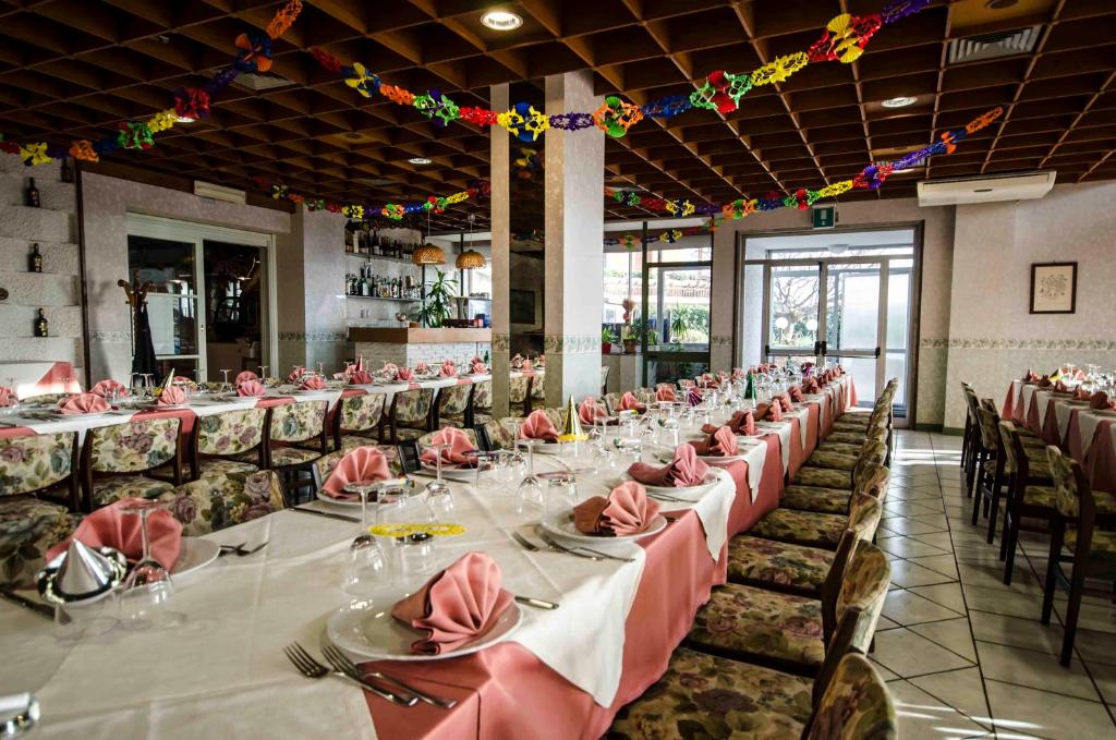une grande salle à manger avec de longues tables et chaises dans l'établissement Hotel Tarconte, à Tarquinia