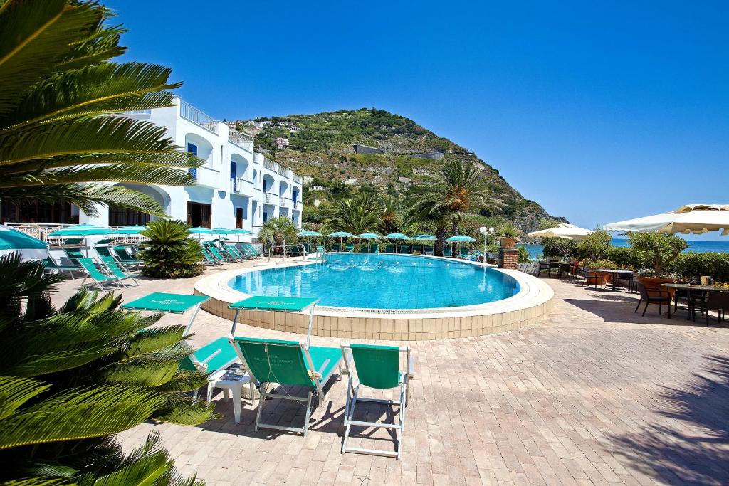 - une piscine avec des chaises et des parasols dans un complexe dans l'établissement Parco Smeraldo Appartamenti, à Ischia