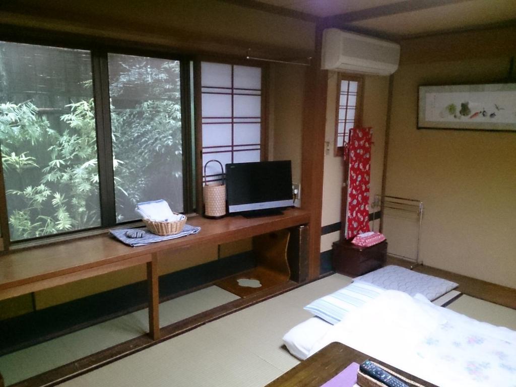 une pièce avec un bureau avec une télévision et une fenêtre dans l'établissement Ryokan Nakajimaya, à Kyoto