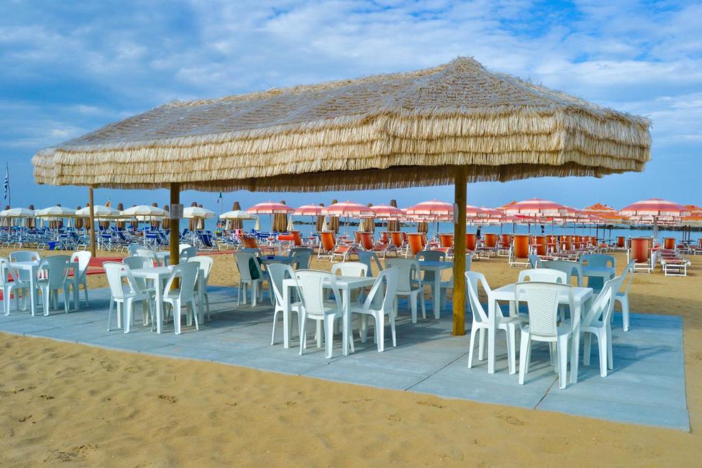- une plage avec des tables et des chaises sous un grand parasol de paille dans l'établissement Hotel Corallo, à Francavilla al Mare
