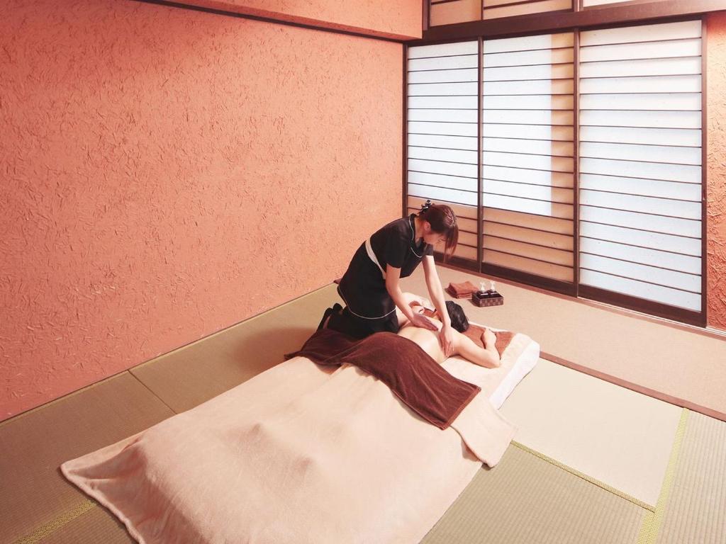 une femme assise sur un lit dans une pièce dans l'établissement Arujisu, à Izu