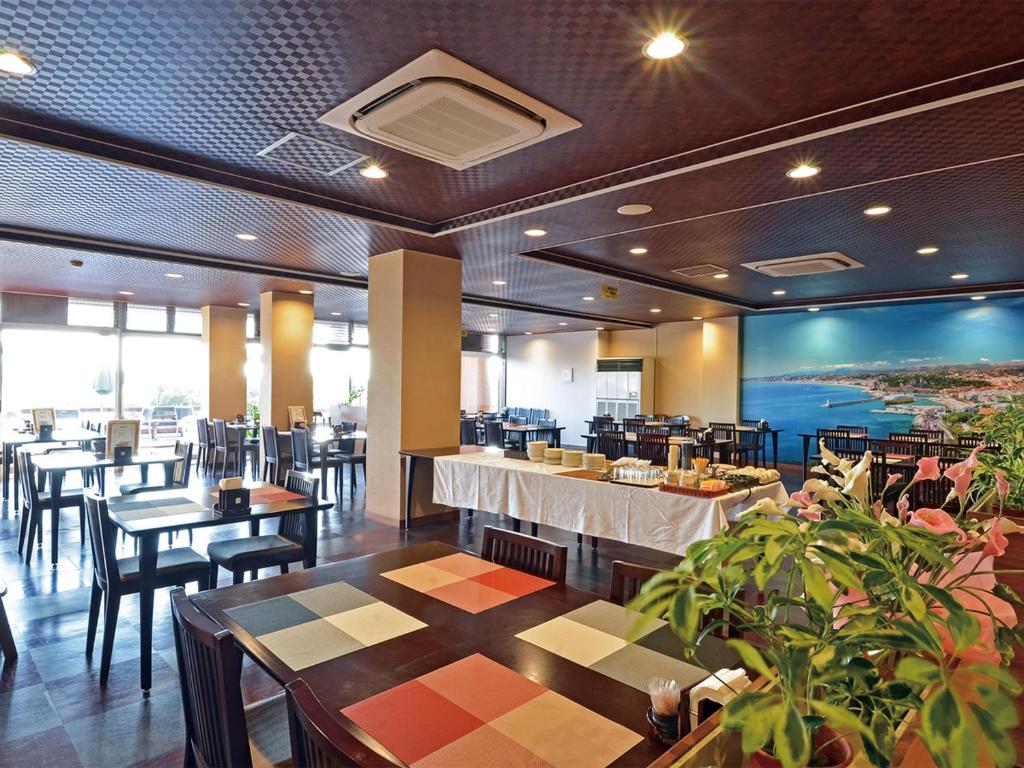 un restaurant avec des tables et des chaises et un grand écran dans l'établissement Iioka Shiosai Hotel, à Asahi