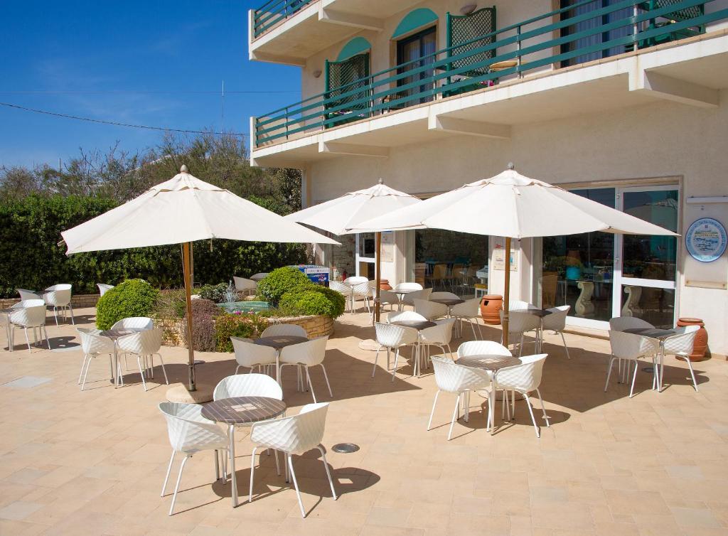 un patio avec des chaises blanches, des tables et des parasols dans l'établissement Hotel Terminal - Caroli Hotels, à Leuca