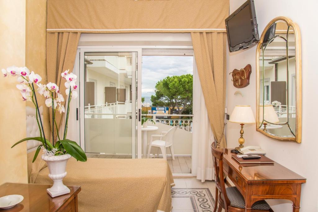 Cette chambre comprend un lit et une table avec un miroir. dans l'établissement Hotel Miramare, à Lignano Sabbiadoro