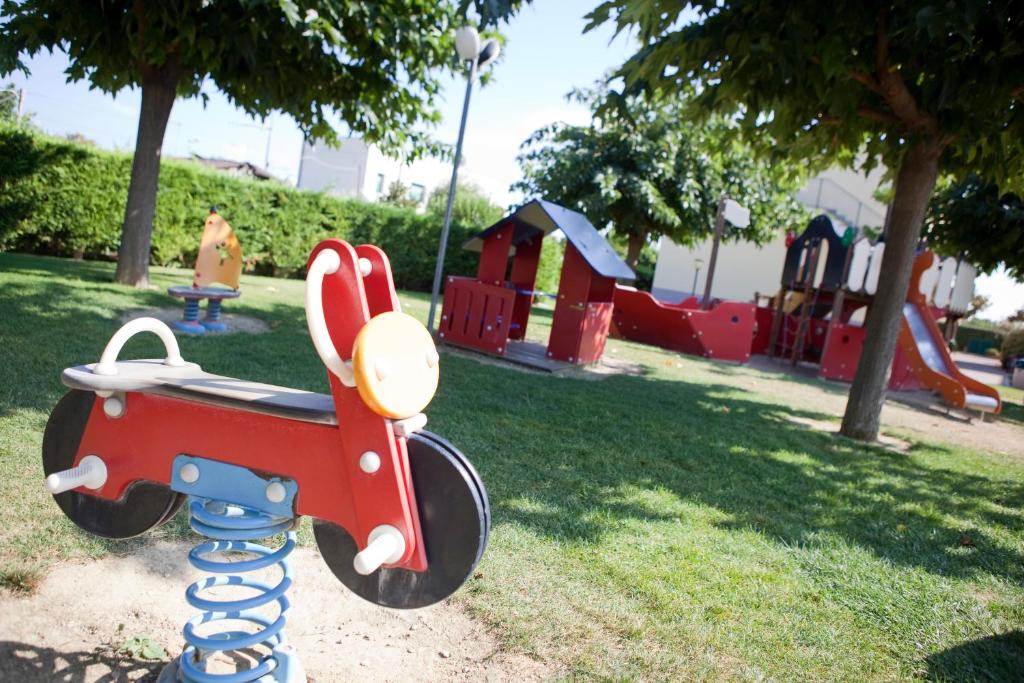 un parc avec une aire de jeux équipée d'un appareil de jouets rouges dans l'établissement Residence Borgomare, à Albenga