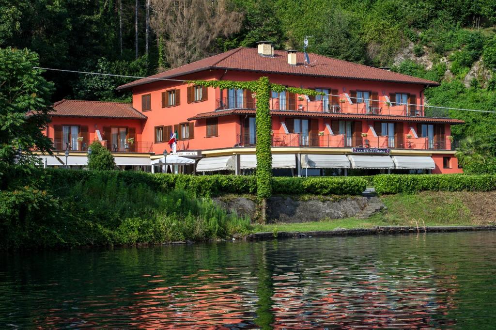 un grand bâtiment orange à côté d'une nappe d'eau dans l'établissement Hotel & Residence La Sibilla Cusiana, à Pettenasco