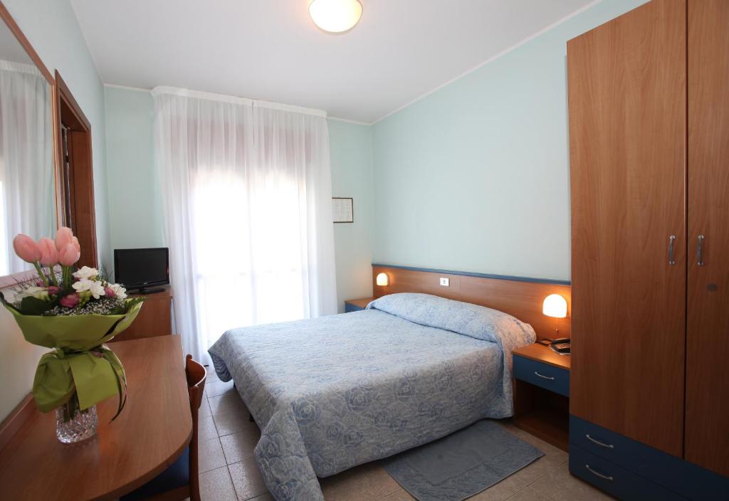 une chambre d'hôtel avec un lit et un vase de fleurs dans l'établissement Albergo Ridente, à Lido di Jesolo