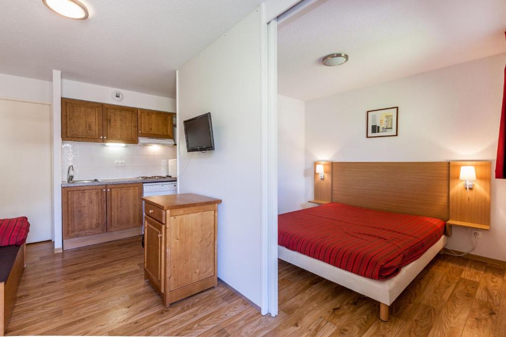 Cet appartement comprend une chambre avec un lit rouge et une cuisine. dans l'établissement Les Cimes Du Val D'Allos, à La Foux 37 autres photos