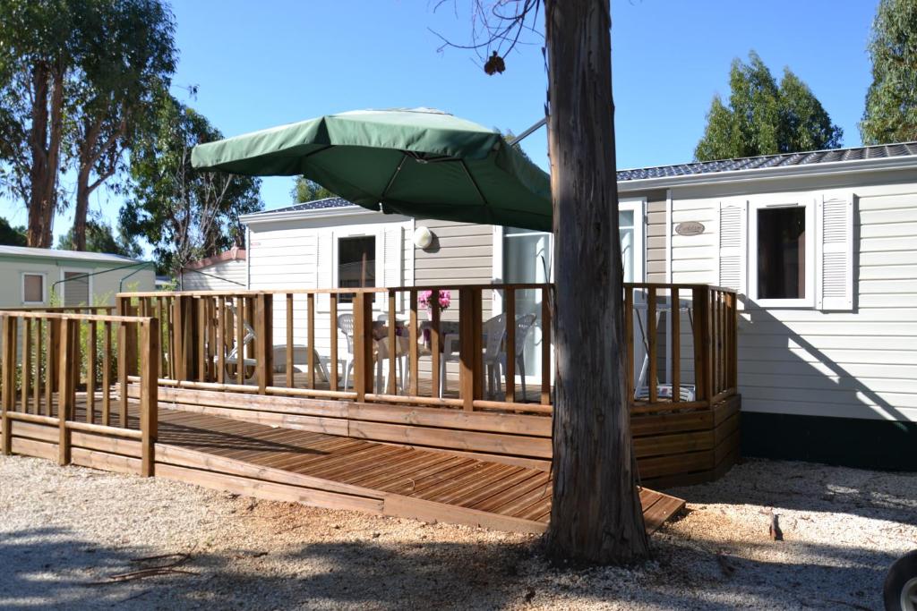 une terrasse avec un parasol vert à côté d'un arbre dans l'établissement Camping Parc Valrose, à La Londe-les-Maures