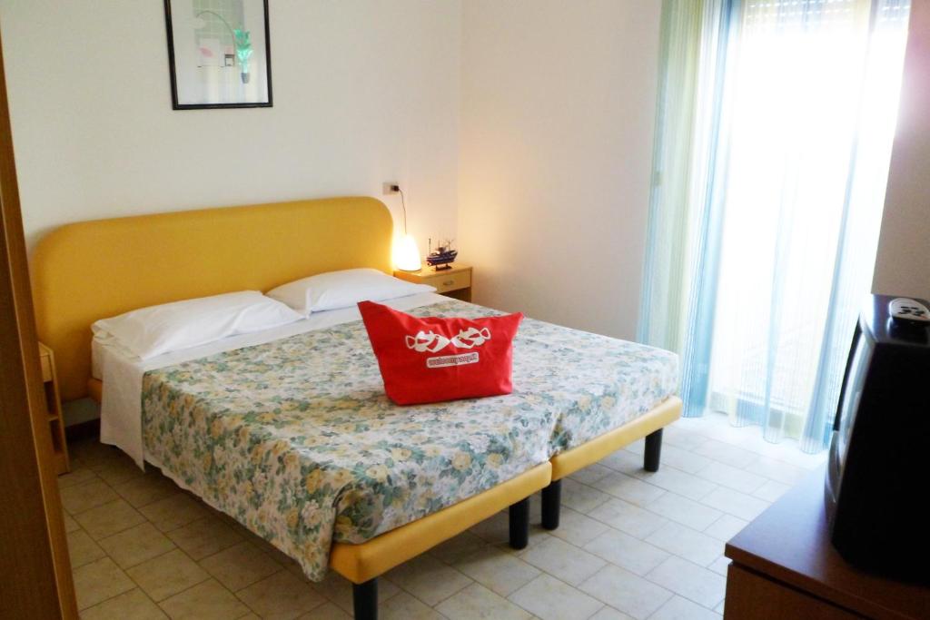 une chambre avec un lit avec un oreiller rouge dessus dans l'établissement B&B Domus Mea, à Cesenatico